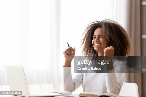 Colegiala africana sentada en el escritorio se siente feliz recibido gran noticia Colegiala africana sentada en el escritorio se siente feliz recibido gran noticia