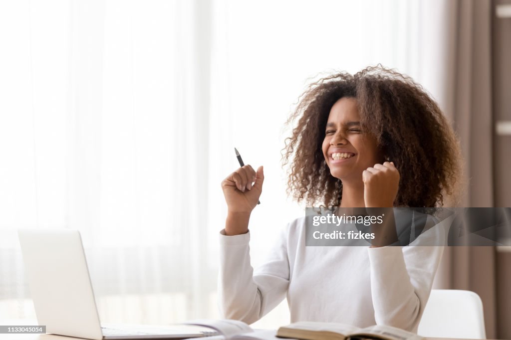 African schoolgirl sitting at desk feels happy received great news