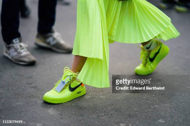 Guest wears a neon green asymmetric pleated skirt, white Nike ankle socks, neon green Nike sneakers, outside Ann Demeulemeester, during Paris Fashion...