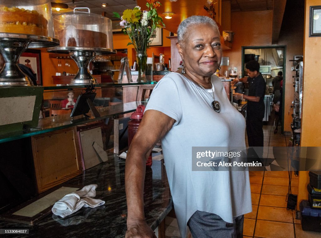 Retrato sincero da mulher de negócios preta sênior ativa em seu restaurante local pequeno