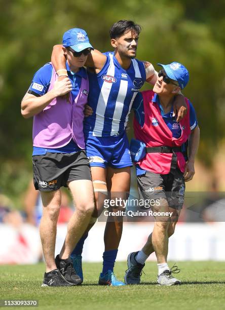 Aaron Hall of the Kangaroos is helped from the ground by trainers during the 2019 JLT Community Series AFL match between the North Melbourne...
