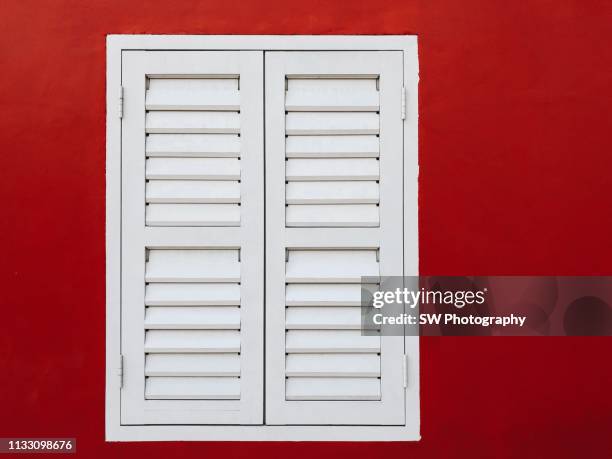 a pure white window on red wall - fensterladen stock-fotos und bilder