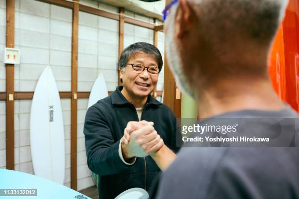 owner who shakes hands with customers on smile in shop - business smile stockfoto's en -beelden