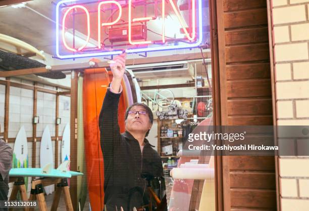 male business owner turning on neon open sign in shop window - opening door stockfoto's en -beelden