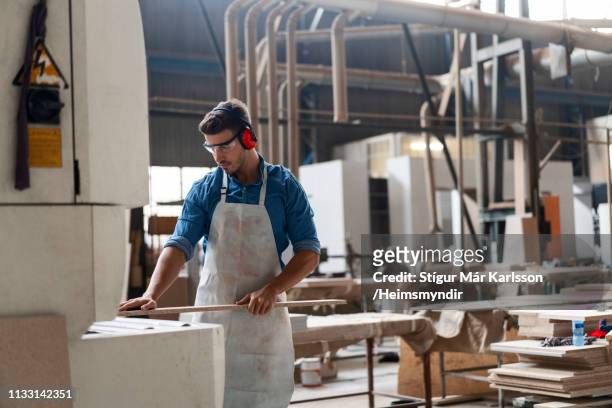 carpenter inserting wood in machine at factory - inserting imagens e fotografias de stock