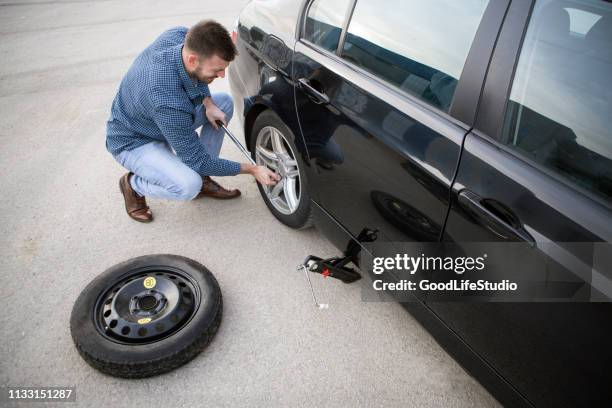 man changing a flat tire - wheel stock pictures, royalty-free photos & images