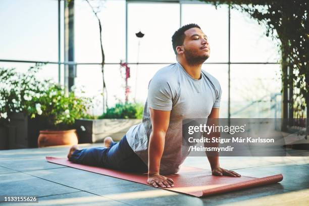 jonge man het beoefenen van opwaartse gericht hond poseren - yoga stockfoto's en -beelden