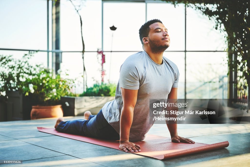 Homem novo que pratica o pose ascendente do cão do revestimento