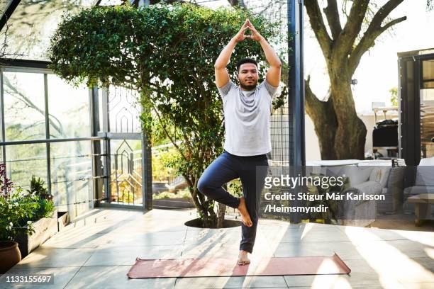 man practicing tree pose in yoga class - tree position stock pictures, royalty-free photos & images
