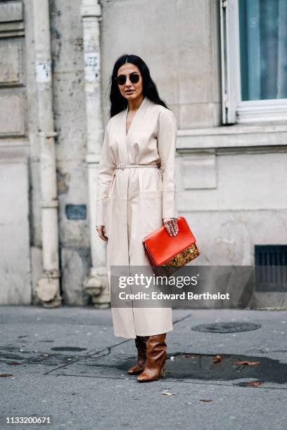 Guest wears sunglasses, a cream-color kimono-style leather coat, brown boots with python pattern heels, a brown alligator pattern bag with a red flap...