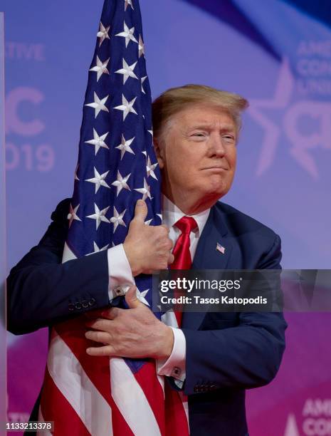 President Donald Trump hugs the U.S. Flag during CPAC 2019 on March 02, 2019 in National Harbor, Maryland. The American Conservative Union hosts the...