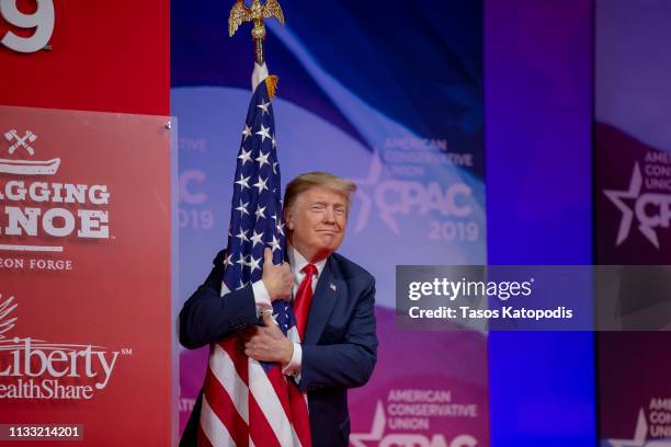 President Donald Trump hugs the U.S. Flag during CPAC 2019 on March 02, 2019 in National Harbor, Maryland. The American Conservative Union hosts the...