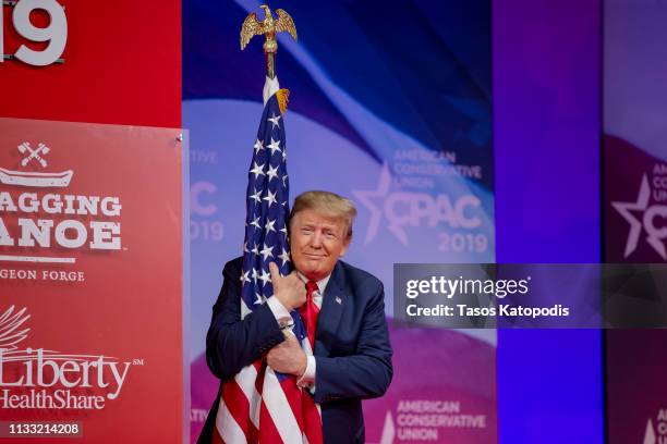 President Donald Trump hugs the U.S. Flag during CPAC 2019 on March 02, 2019 in National Harbor, Maryland. The American Conservative Union hosts the...