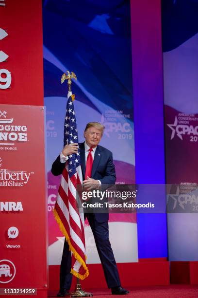 President Donald Trump hugs the U.S. Flag during CPAC 2019 on March 02, 2019 in National Harbor, Maryland. The American Conservative Union hosts the...