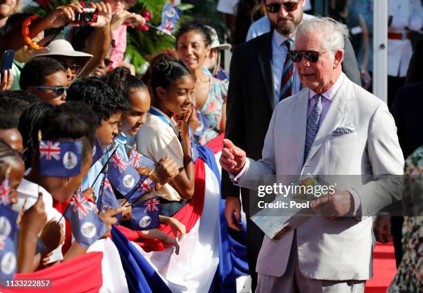 Prince Charles is given a picture book names "Georgie and the Stingray City" as he interacts with children during his arrival at the Owen Roberts...