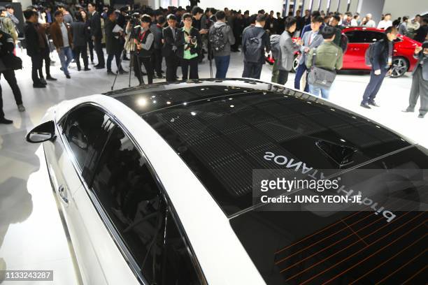 Visitors take a look at Hyundai Motor's Sonata Hybrid equipped with solar panels on the rooftop during a press preview of the Seoul Motor Show in...