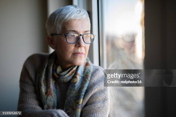 portrait of beautiful mature woman relaxing by the window - 60 64 years stock pictures, royalty-free photos & images