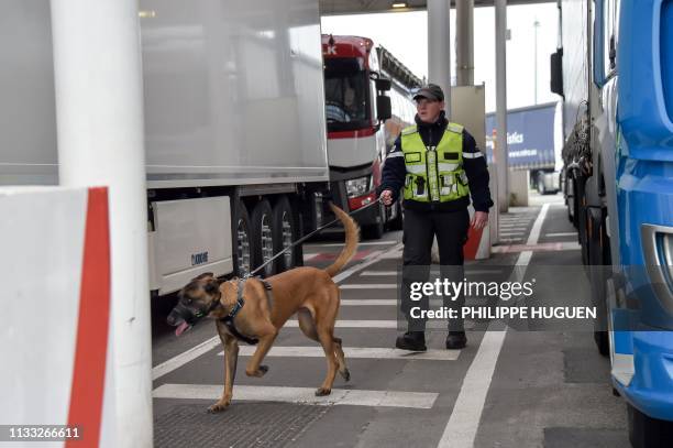 Security agent controls trucks assisted with a dog, on March 28, 2019 at the Coquelles Eurotunnel border post, a new border inspection post for...