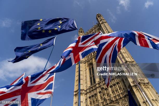 Union and EU flags flutter outside the Houses of Parliament in Westminster, London on March 28, 2019. - Faced with losing all control over the Brexit...
