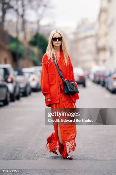 Charlotte Groeneveld wears sunglasses, a red jacket, a red fringed dress, Balenciaga shoes, a black leather bag, outside Elie Saab, during Paris...