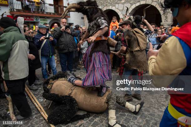 Man carrying billy goats’ horns and goat skins known as ‘Trangas’ jumps on top of a man dressed as a bear during Bielsa traditional carnival on March...