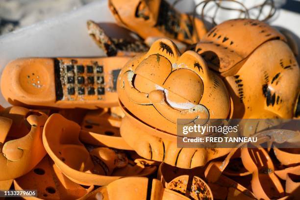 Spare parts of plastic 'Garfield' phones are displayed on the beach on March 28, 2019 in Plouarzel, western France, after being collected from a sea...