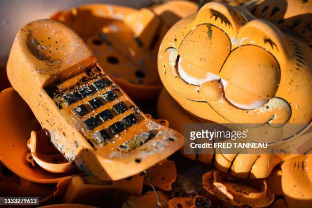 Spare parts of plastic 'Garfield' phones are displayed on the beach on March 28, 2019 in Plouarzel, western France, after being collected from a sea...