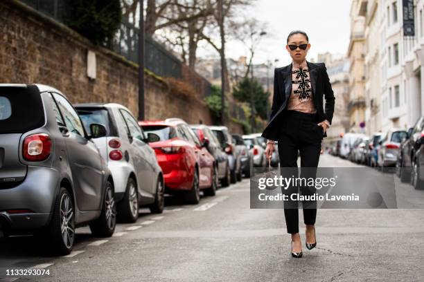 Jaime Xie, wearing black blazer and pants, pink shirt, back Saint Laurent heels and sunglasses, is seen outside Vivienne Westwood on Day 6 Paris...