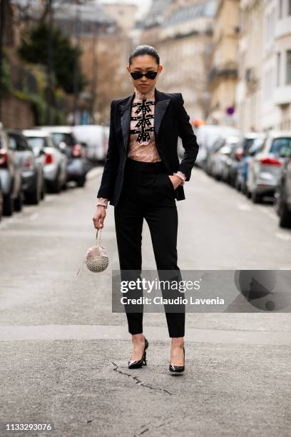 Jaime Xie, wearing black blazer and pants, pink shirt, back Saint Laurent heels and sunglasses, is seen outside Vivienne Westwood on Day 6 Paris...