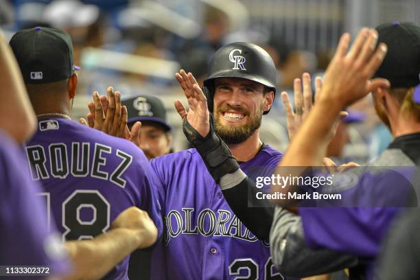 David Dahl of the Colorado Rockies celebrates with teammates in the dugout in the fifth inning against the Miami Marlins during Opening Day at...