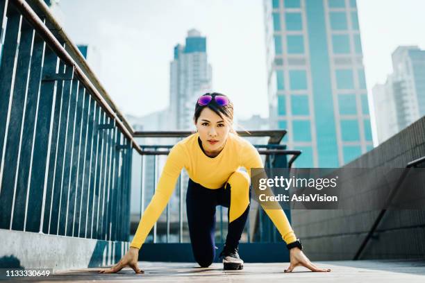 determined female runner all set to run on city bridge against urban cityscape - china athlete woman stock pictures, royalty-free photos & images