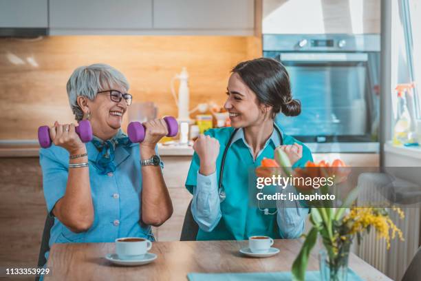 docteur aidant le patient aîné dans l'haltère de levage - occupational therapy kitchen photos et images de collection