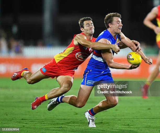 Jack Macrae of the Bulldogs is tackled by Lachie Weller of the Suns during the 2019 JLT Community Series AFL match between the Gold Coast Suns and...