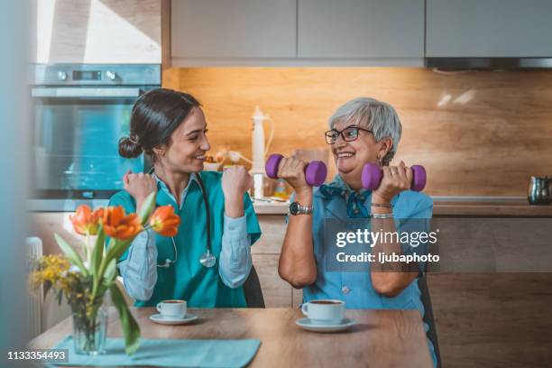 krankenschwester hilft seniorin beim heben - ergotherapie stock-fotos und bilder