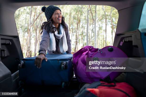 femme heureuse prenant une pause de voyage de route, prenant un sac du tronc de voiture. - car camping luggage photos et images de collection