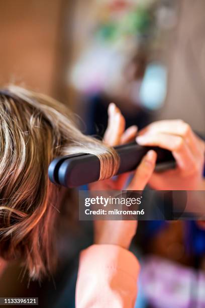 hairdresser curling womens hair at a salon - hair curlers stockfoto's en -beelden