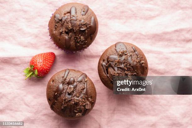 chocolate muffins on pink background top view - muffin top stock-fotos und bilder