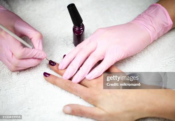 nail technician in gloves painting clients nails - nail salon stock pictures, royalty-free photos & images