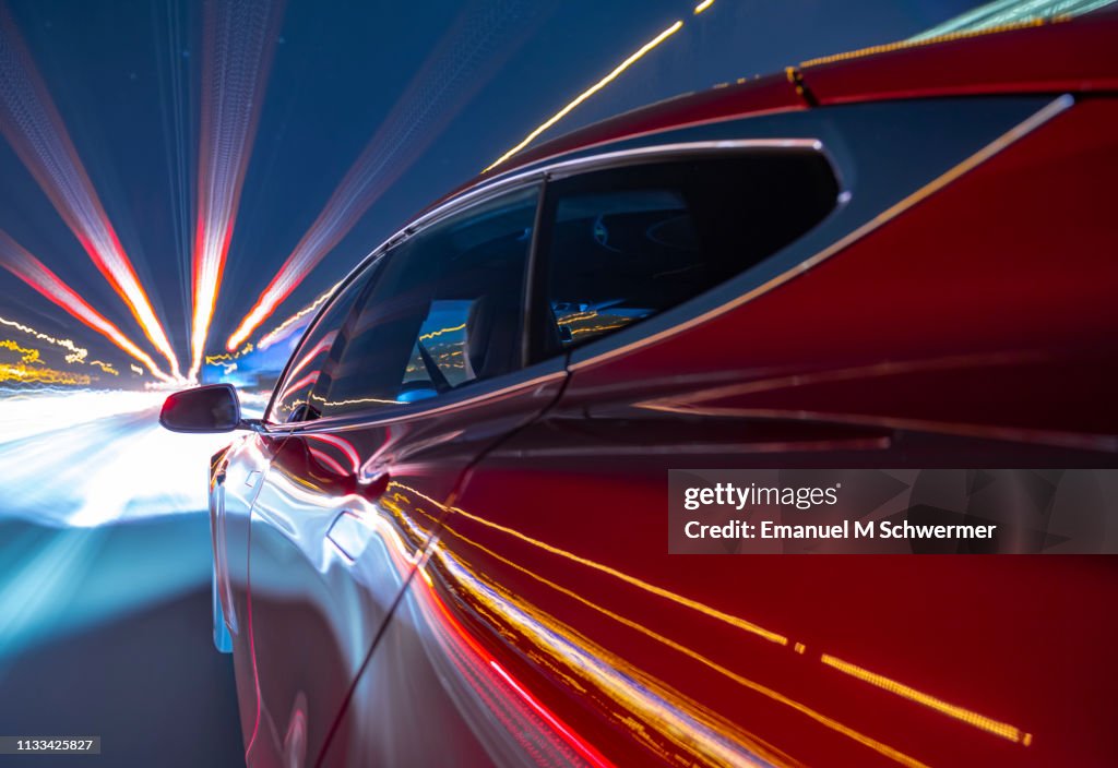 Electric powered red car driving on German Autobahn.