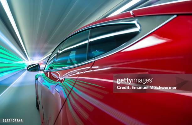 electric powered red coloured us car drives and exits a tunnel on highway in the city munich. - automotive design stock-fotos und bilder