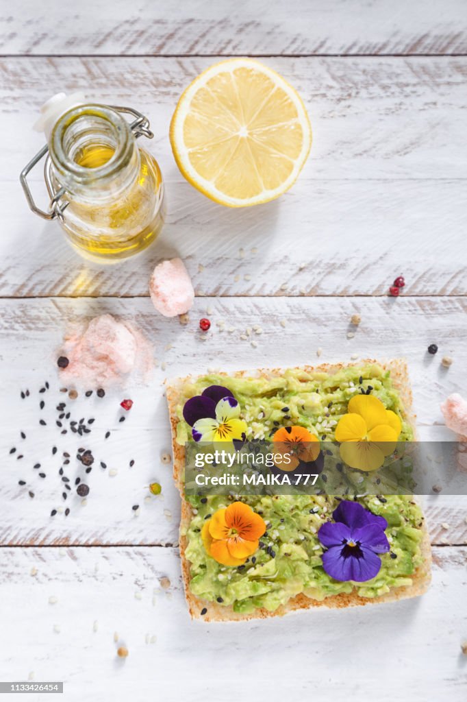 Smashed avocado toast with pepper chilli, sesame seeds, olive oil, Himalayan salt, fresh lemon juice and edible flowers.