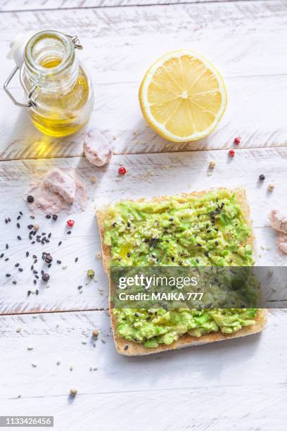 smashed avocado toast with pepper chilli, sesame seeds, olive oil, himalayan salt and fresh lemon juice. - avacado oil stock pictures, royalty-free photos & images