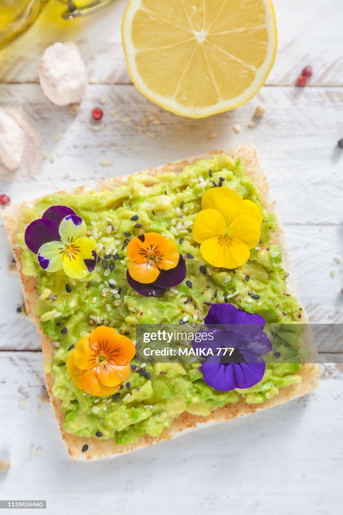 Smashed avocado toast with pepper chilli, sesame seeds, olive oil, Himalayan salt, fresh lemon juice and edible flowers.