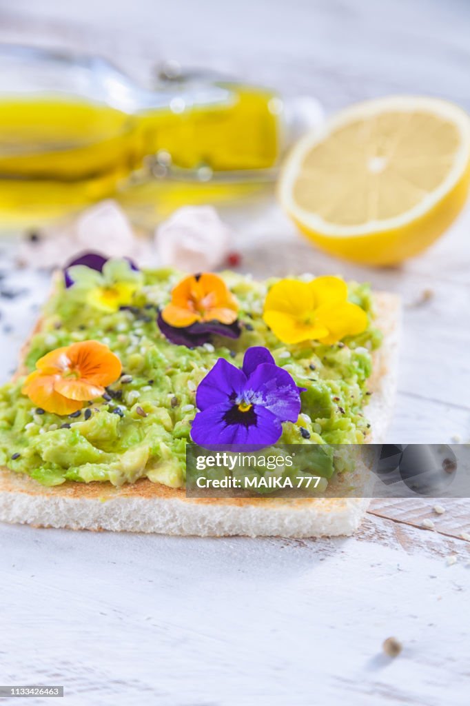 Smashed avocado toast with pepper chilli, sesame seeds, olive oil, Himalayan salt, fresh lemon juice and edible flowers.