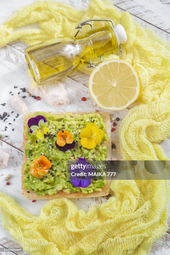 Smashed avocado toast with pepper chilli, sesame seeds, olive oil, Himalayan salt, fresh lemon juice and edible flowers.