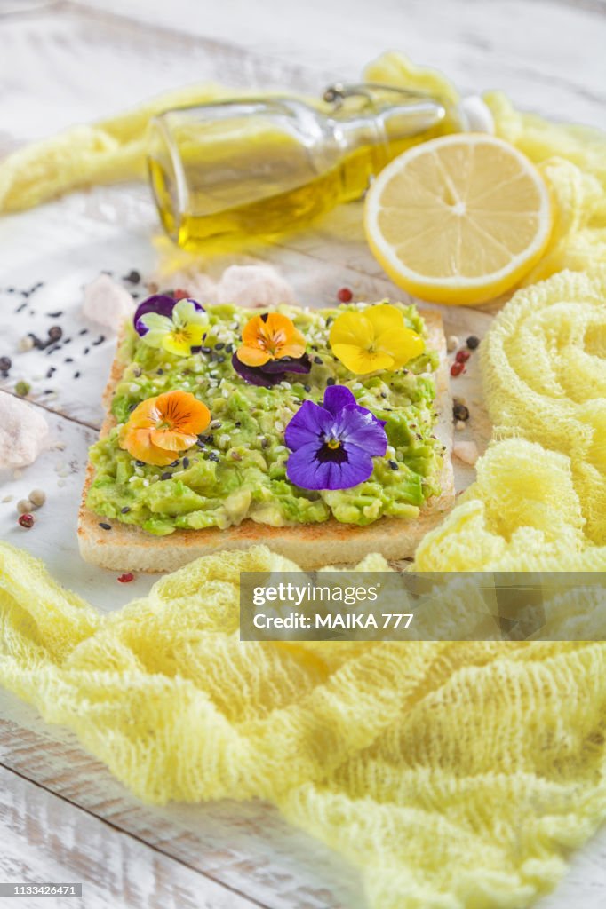 Smashed avocado toast with pepper chilli, sesame seeds, olive oil, Himalayan salt, fresh lemon juice and edible flowers.