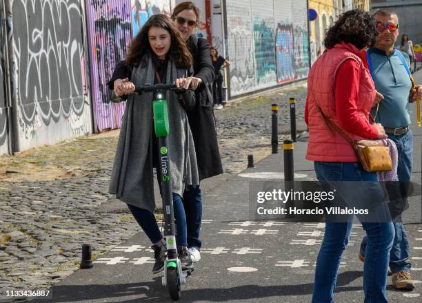 Two women pass by a couple while riding an e-scooter on the Ciclovia Lisboa Cidade by Tagus River in Cais Gás on March 03, 2019 in Lisbon, Portugal....