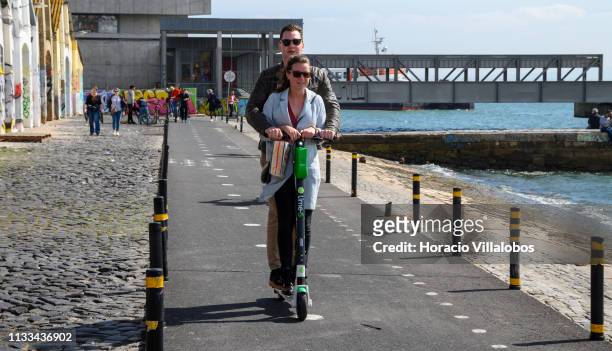 Couple rides an e-scooter on the Ciclovia Lisboa Cidade by Tagus River in Cais Gás on March 03, 2019 in Lisbon, Portugal. Since their introduction in...