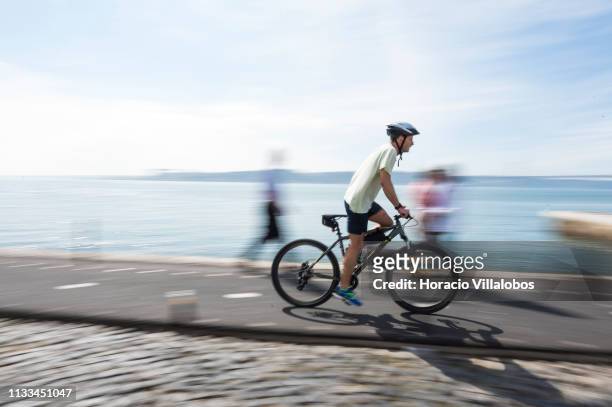 Man rides a bicycle along the Ciclovia Lisboa Cidade by Tagus River in Cais Gás on March 03, 2019 in Lisbon, Portugal. The city has several...
