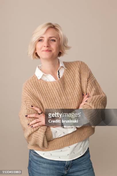 retrato do estúdio de uma mulher loura dos anos de idade 40 atrativa em uma camisola bege em um fundo bege - beige background - fotografias e filmes do acervo